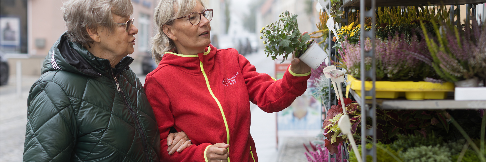 Helferin des DRK mit einer Senioren beim Einkauf von Grünpflanzen