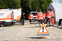 Rettungskräfte des Deutschen Roten Kreuzes in Warnwesten an Unfallhilfsstelle mit Einsatzfahrzeugen und Absperrband