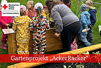 Kinder und Erwachsene arbeiten an einem Hochbeet.