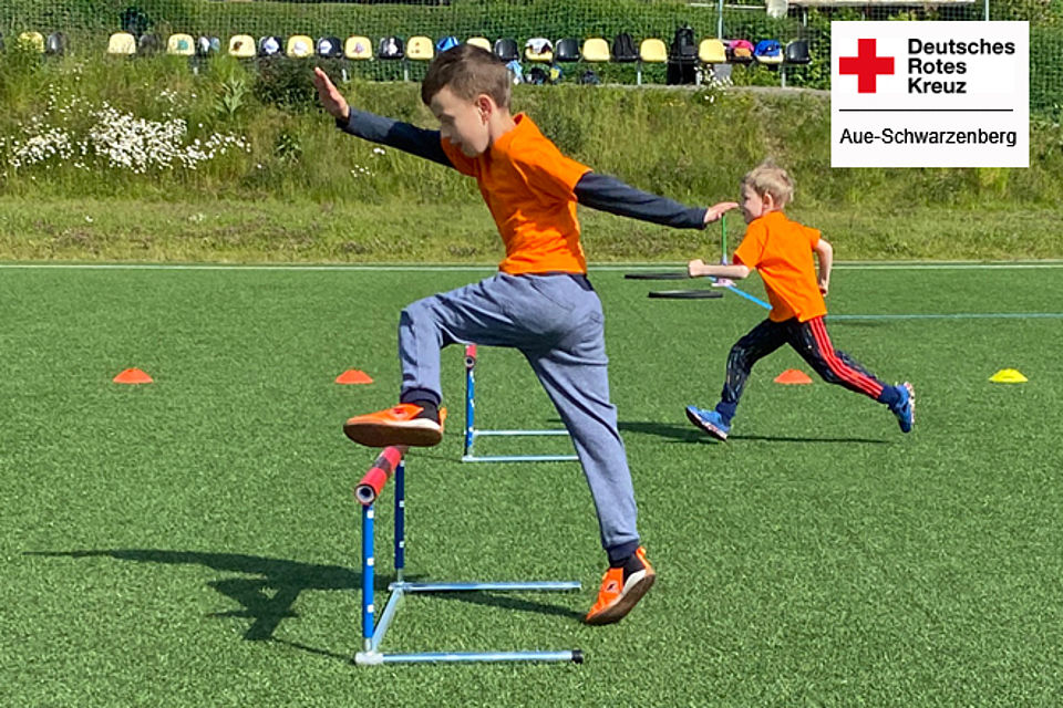 Schuanfänger-Sportfest - zwei Jungen beim Hindernislauf springen über eine Hürde