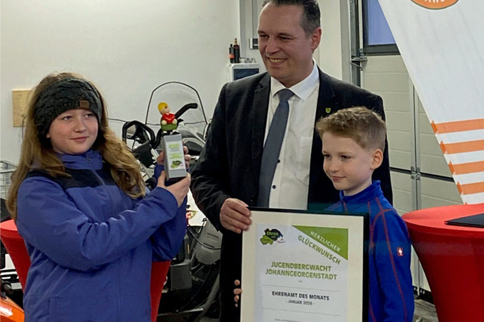 660_2026_Ehrenamt_des_Monats2.jpg Landrat Rico Anton und zwei Kinder der Jugendbergwacht Johanngeorgenstadt, ein Junge hält die gerahmte Urkunde für das Ehrenamt des Monats