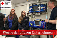 Woche der offenen Unternehmen: zwei DRK Mitarbeiter stellen ein Gerät im RTW vor