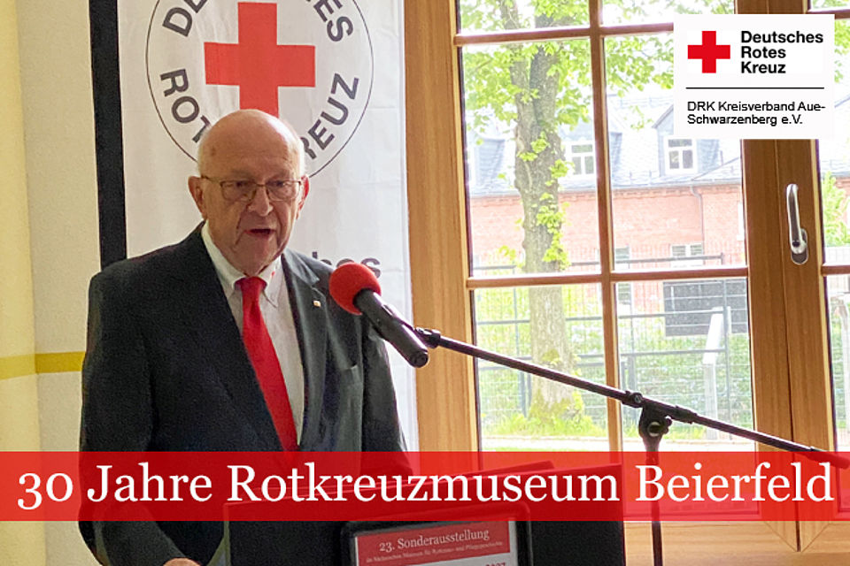 30 Jahre Rotkreuzmuseum Beierfeld: Thomas Klemp am Rednerpult vor eine DRK-Fahne