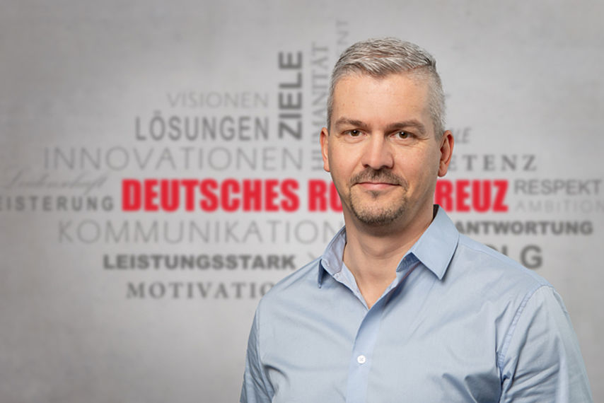 Mitarbeiterfoto mit Rotkreuz-Hintergrund