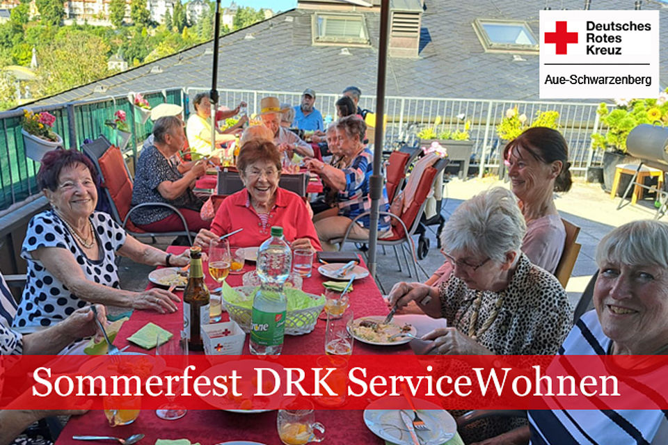 Sommerfest ServiceWohnen: Senioren sitzen auf der Dachterrasse unter einem großen Sonnenschirm beim Abendessen