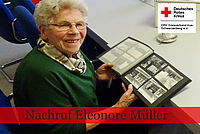 Ältere Frau sitzt am Tisch und schaut in eine altes Fotoalbum mit Schwarz-Weiß-Bildern.