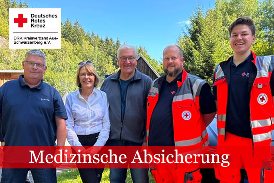 Zwei Einsatzkräfte in DRK-Kleidung sowie ein Arzt mit blauem Poloshirt rahmen den Bundespräsidenten Frank-Walter Steinmeier und dessen Frau ein.