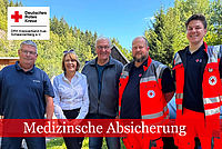 Zwei Einsatzkräfte in DRK-Kleidung sowie ein Arzt mit blauem Poloshirt rahmen den Bundespräsidenten Frank-Walter Steinmeier und dessen Frau ein.