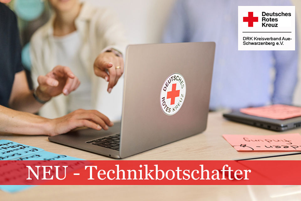 660_2025_Technikbotschafter.jpg Laptop mit DRK-Logo steht auf einem Tisch. Mehrere Hände zeigen darauf.