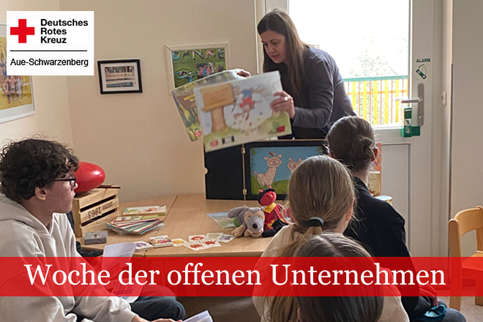 Woche der offenen Unternehmen: Erzieherin präsentiert ein Buch, mehrere Schüler sitzen und schauen zu ihr.