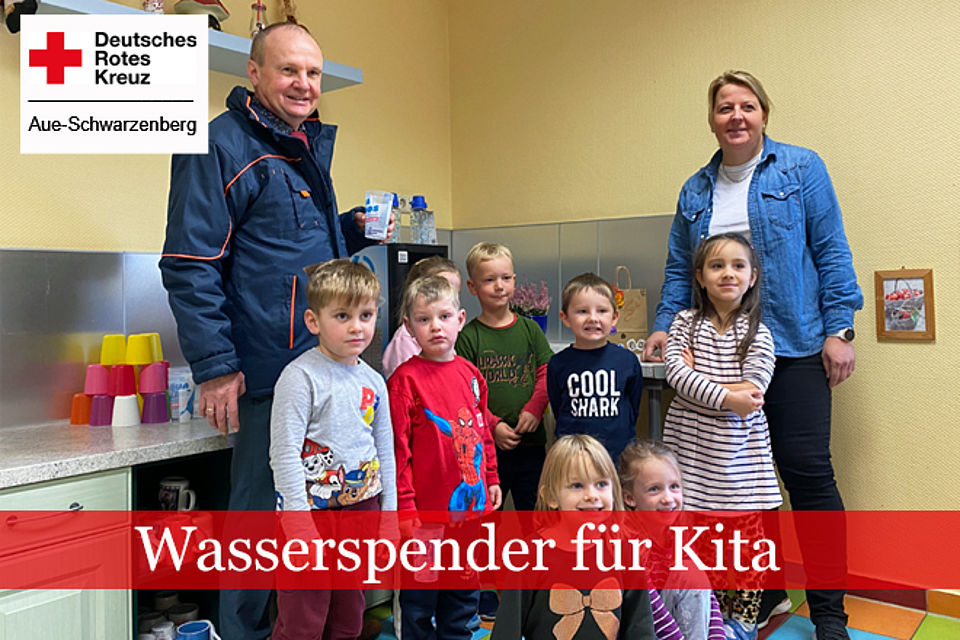 Dr. Frank Kippig von den Wasserwerken Westerzgebirge und Kitaleiterin Claudia Janik stehen mit einigen Kindergartenkindern vor dem neuen Wasserspender.