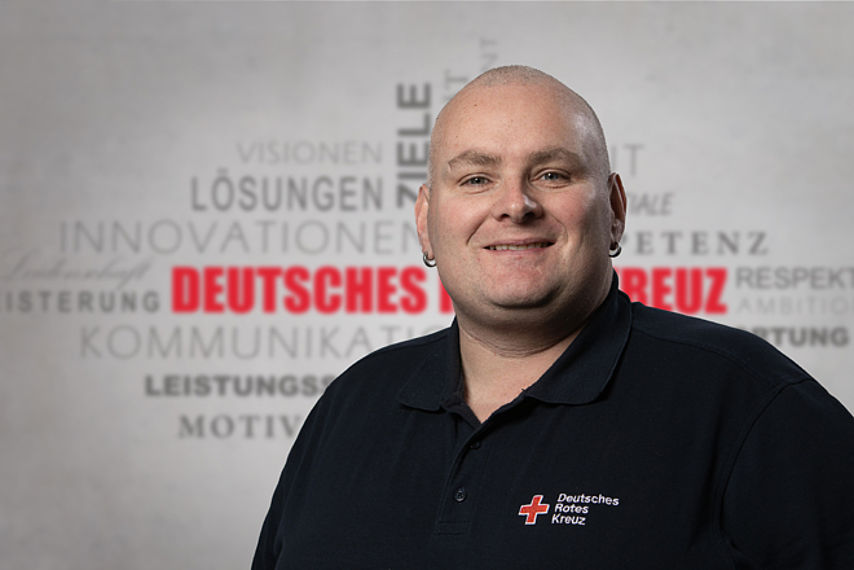 Mitarbeiterfoto mit Rotkreuz-Hintergrund