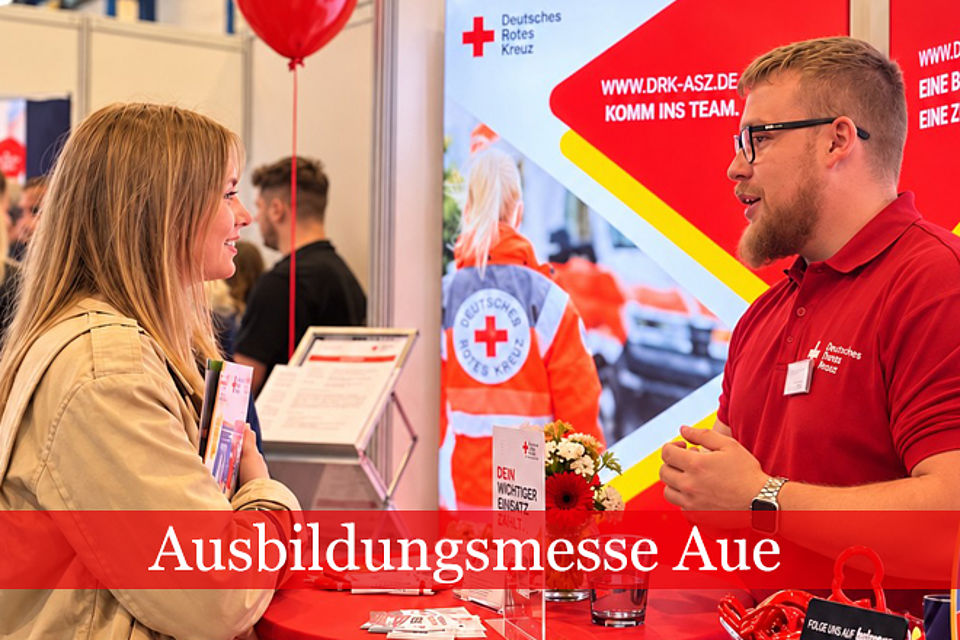 Ein Mann in rotem DRK-Shirt im Gespräch mit einer Messebesucherin.