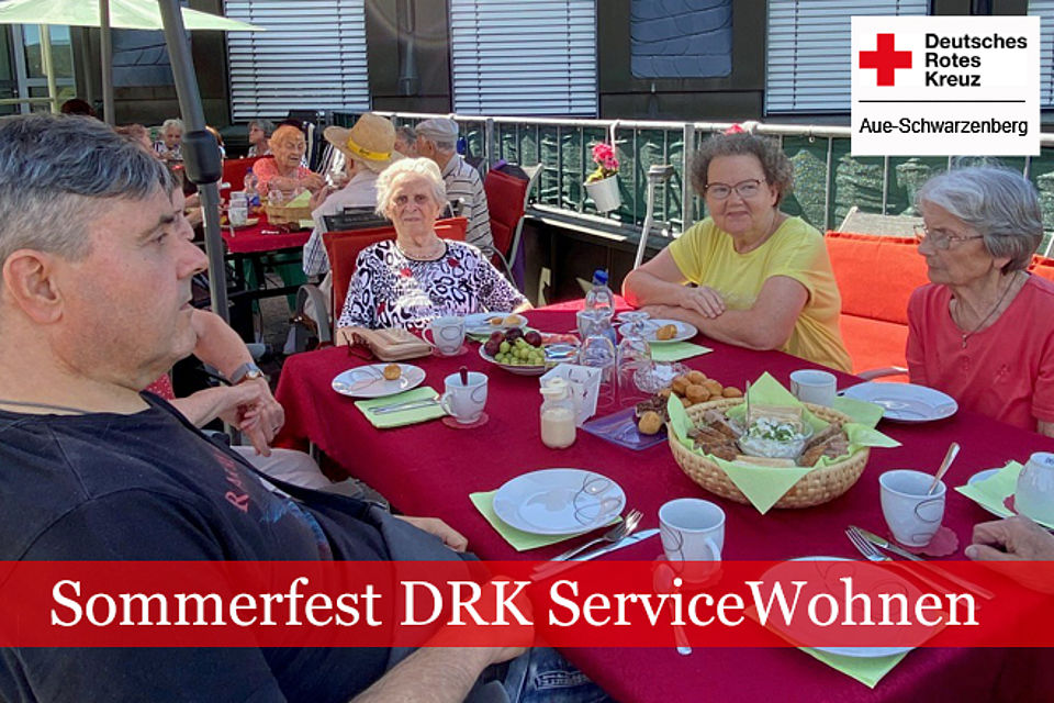 Sommerfest ServiceWohnen: Senioren sitzen an gedeckter Kaffeetafel im Freien