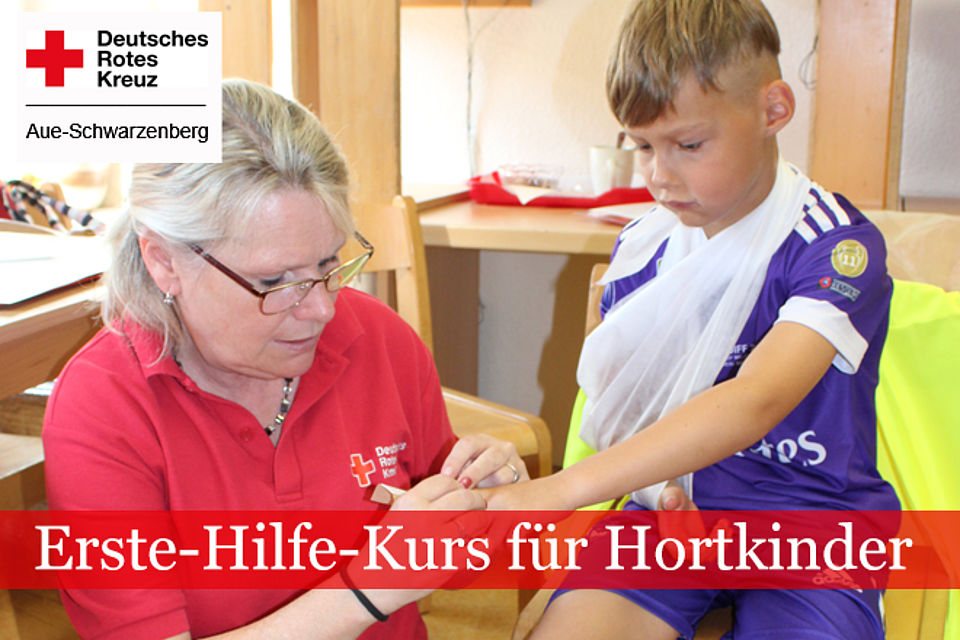 660_2026_Kita_Schneeberg_EH_1.jpg Erste Hilfe für Hortkinder: DRK-Ausbilderin im roten Shirt zeigt einem Kind das Anlegen eines Verbandes.