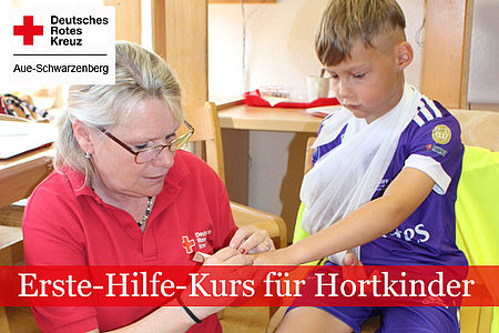 Erste Hilfe für Hortkinder: DRK-Ausbilderin im roten Shirt zeigt einem Kind das Anlegen eines Verbandes.