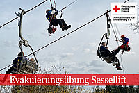 Retter in Bergwachtkleidung nähern sich an einem Sessellift den Personen, die im Lift festsitzen.