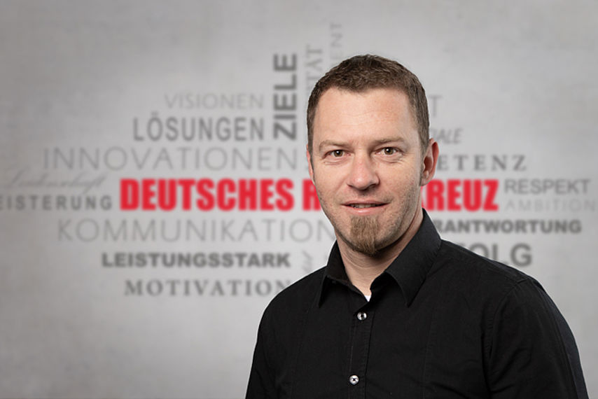 Mitarbeiterfoto mit Rotkreuz-Hintergrund