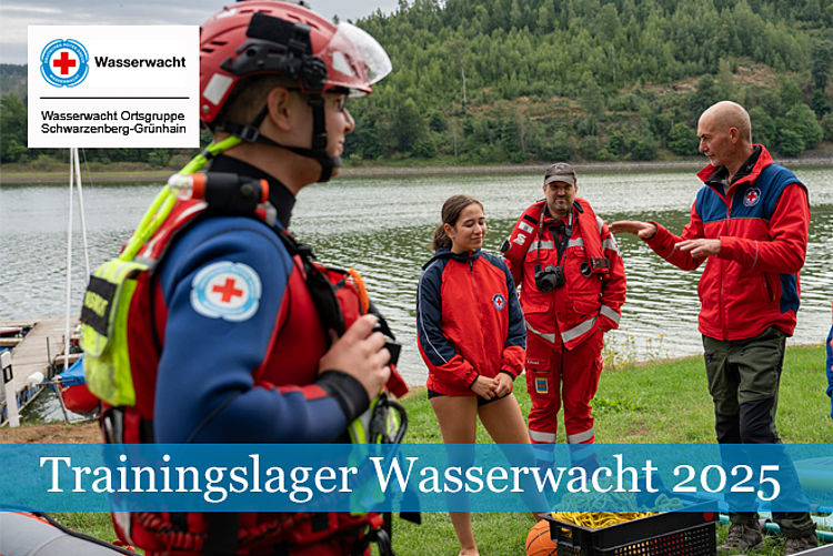 Trainingslager Wasserwacht 2025: Wasserretter und Teilnehmer in roter Einsatzkleidung stehen am Ufer eines Sees, Ausbilder stellt Ausrüstung vor