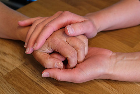 jüngere Hände umfassen eine ältere Hand und spenden Trost