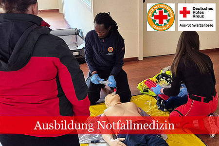Drei Teilnehmer an einem Sanitätslehrgang knien auf dem Boden und trainieren die Beatmung einer Übungspuppe.