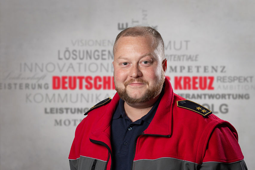 Mitarbeiterfoto mit Rotkreuz-Hintergrund