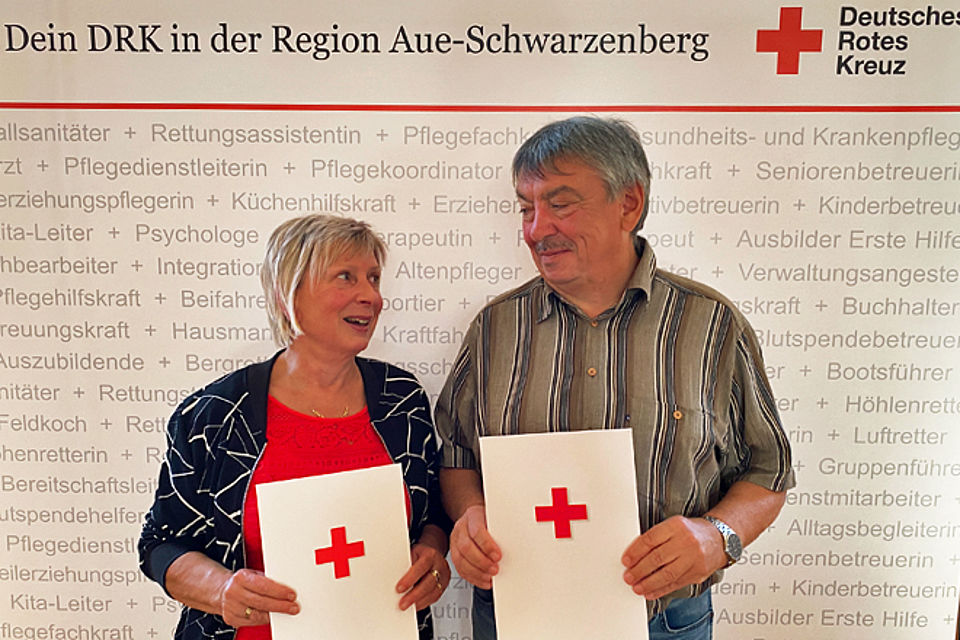 Ehrepaar vor DRK Fotowand mit Urkunde zur Blutspenderehrung