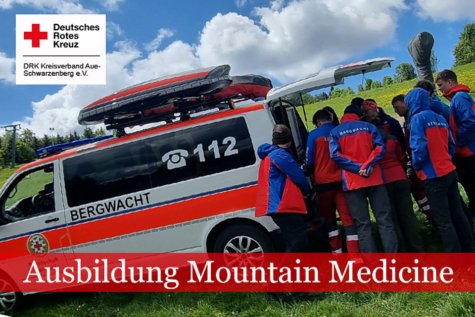 Angehörige der Bergwacht in Einsatzkleidung besichtigen ein Einsatzfahrzeug im Rahmen ihrer Ausbildung.