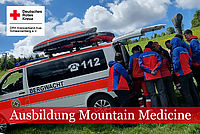 Angehörige der Bergwacht in Einsatzkleidung besichtigen ein Einsatzfahrzeug im Rahmen ihrer Ausbildung.