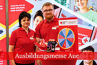 Ein Mann und eine Frau stehen in DRK Kleidung vor einem Messestand.