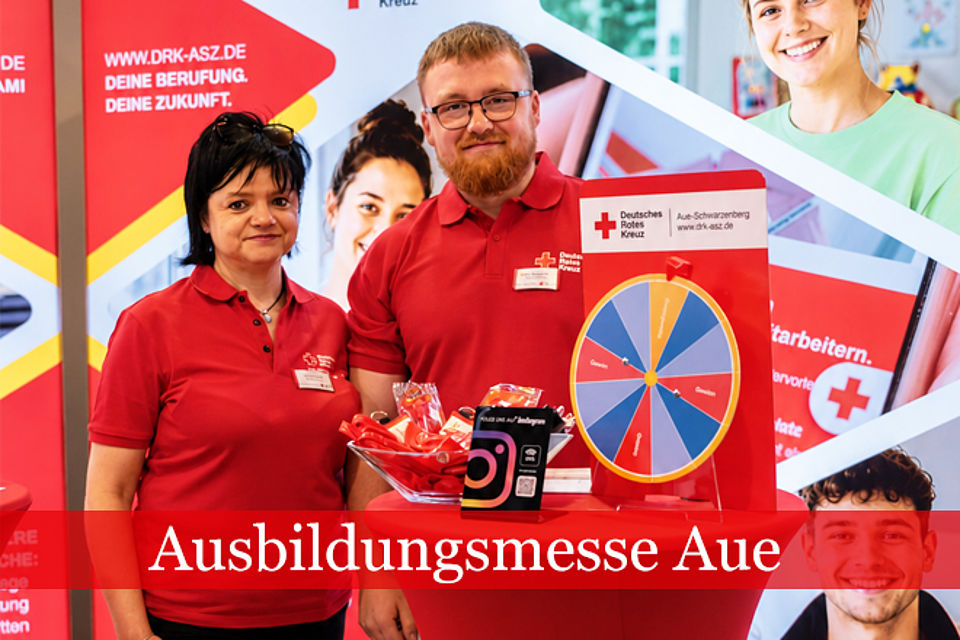 Ein Mann und eine Frau stehen in DRK Kleidung vor einem Messestand.