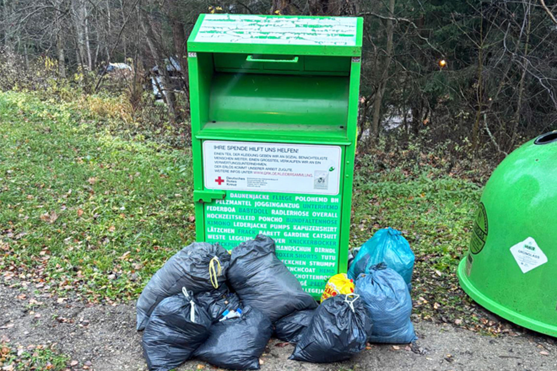 Gründer DRK Altkleidercontainer mit Kleidersäcken, die neben dem Container abgelegt wurden