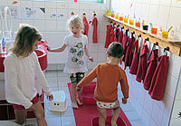drei Kinder im Waschraum der Kita beim Wassertreten