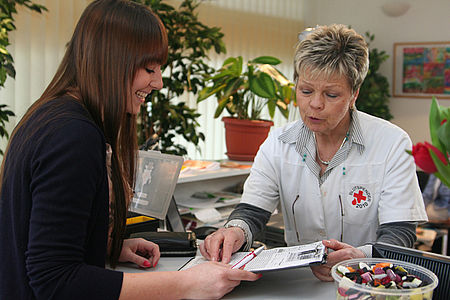 Blutspendehelferin des DRK erklärt einer Spenderin den Fragebogen