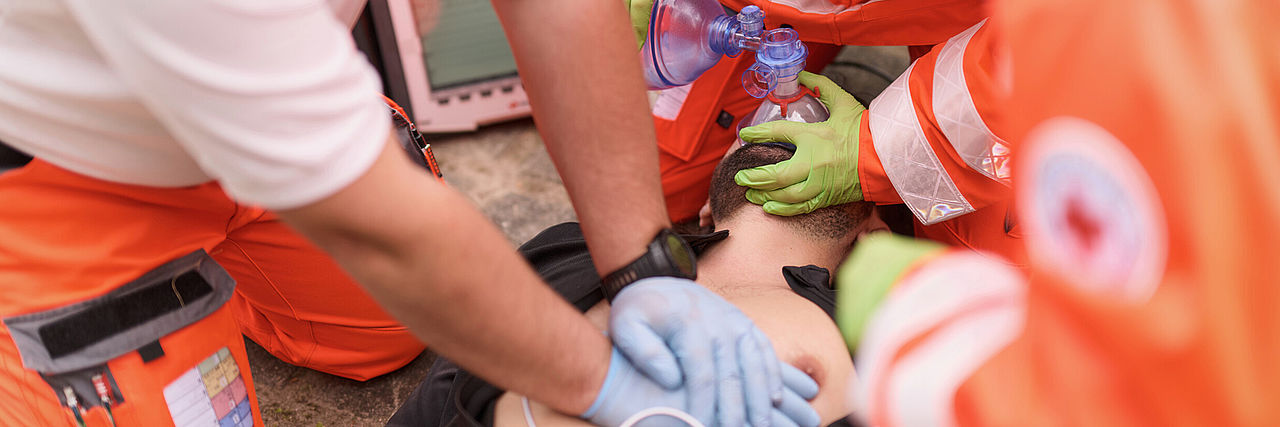 Mitarbeitende vom Rettungsdienst bei der Wiederbelebung: Hände mit Handschuhen bei der Herzdruckmassagee